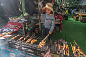 Laotian boy at the grill, near Kuang Si waterfall, Laos