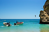 Mann springt von Felsen am Strand von Benagil, Algarve, Portugal