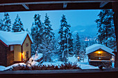 Abendlicher Blick auf zwei beleuchtete Holzhütten im Winter, Heggenes, Norwegen