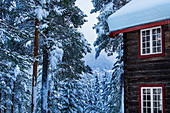 Eingeschneites Holzhaus im Winter bei Heggenes, Norwegen
