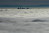 Silhouetted skyscraper buildings above clouds, Vancouver, British Columbia