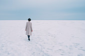 Woman in coat and hat walking in snow covered landscape