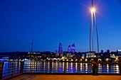 Evening view from the waterfront over Baku Bay to the Flame Towers with illumination, Baku, Caspian Sea, Azerbaijan, Asia