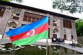 Flag of Azerbaijan and facade of the historic Xan Sarayi Fortress in Sheki, Azerbaijan, Asia