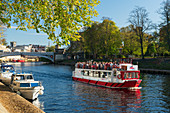 Pleasure boats moored along the River Ouse and a York Boat full with tourists on a sightseeing river cruise, York, Yorkshire, England, United Kingdom, Europe