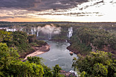 Scenic view of rainforest surrounding splashing Iguazu Falls at dusk, Parana, Brazil