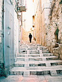 Distant view of traditionally dressed orthodox Jew walking in street of Jerusalem, Israel