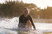 Young woman smiling at camera while surfing near coast,†Kuta, Bali, Indonesia