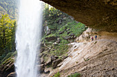 Two people walking over trail behind Pericnik waterfall in alpine Vrata valley near Mojstrana in Triglav National Park, Slovenia