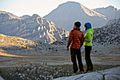 A couple watches sunrise over the mountains from the Puppet Lake Basin on a two-week trek of the Sierra High Route in the John Muir Wilderness in California. The 200-mile route roughly parallels the popular John Muir Trail through the Sierra Nevada Range of California from Kings Canyon National Park to Yosemite National Park. 