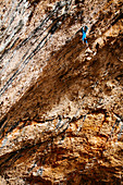 Climber hanging upside down from roof of Santa Linya cave, Catalonia, Spain