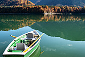 Rowing boat on the Sylvensteinsee, autumn forest in the background, Lenggries, Bavaria, Germany