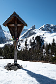 Wooden cross in front of the mountain panorama of the Dolomites in winter, Dolomites, Belluno, Italy