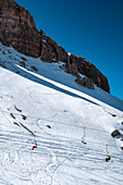 Ski lift in front of the massif of the Cinque Torri in winter with ski tracks in the snow, Dolomites, Cortina d´Ampezzo, Belluna, Italy