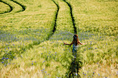Carefree girl walking in sunny, idyllic rural field with wildflowers