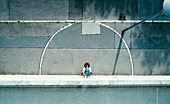 View from above young man meditating on urban sidewalk