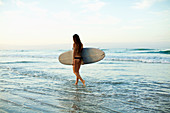 Frau mit Surfbrett am Strand