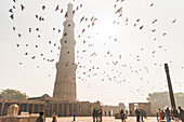 Birds fly over visitors while they take photos of one another at Qutub Minar, UNESCO World Heritage Site, New Delhi, India, Asia