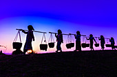 Silhouette of people carrying baskets under sunset sky, Myanmar, Burma