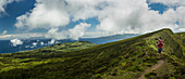 Hiker walking on hilltop dirt path over Cabeco Gordo crater, Faial, Portugal