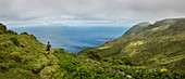 Hiker walking on hilltop path in rural landscape, Azores Islands, Flores, AzoresIslands