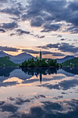Village church and buildings reflected in still lake, Bled, Upper Carniola, Slovenia