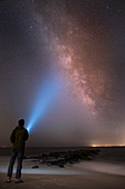 Asiatischer Mann mit leuchtender Taschenlampe am Sternenhimmel, Cape May, New Jersey, USA