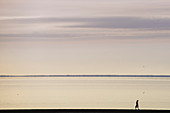 Frau mit langen Haaren flaniert am Strand entlang. Deutschland, Ostfriesland, Norden