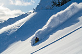 Skifahrer bei Abfahrt durch Tiefschnee im Hochzillertal, Tirol, Österreich