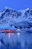 Illuminated slidpollnes and snowy mountains are reflected in fjord, Lofoten, Nordland, Norway