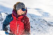 Junge Frau schaufelt mit einer Lawinenschaufel Schnee, Tirol, Österreich