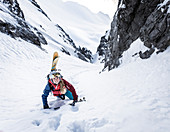 Skialpinistin beim Aufstieg mit Ski ab Rucksack in einer steilen Rinne, Mieminger Kette, Tirol, Österreich