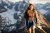 Nahaufnahme einer jungen blonden Frau in kurzer Hose beim Wandern in herrlichen warmen Gegenlicht  mit verschneiten Bergen im Hintergrund, Hinterriss, Karwendel, Tirol, Österreich