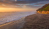 Frau blickt in Sonnenuntergang am Strand an der Westküste Kaliforniens\n