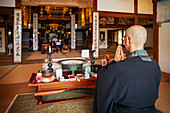 Buddhist priest kneeling in Buddhist temple, praying.