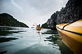 Group of kayakers rowing in a bay amidst limestone karst formations.