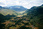 Landscape with valley and mountains under a cloudy sky.