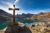 France, Alpes de Haute Provence, Parc National du Mercantour (National park of Mercantour), Haut Verdon, wooden cross by the lake of Allos (2 228m) in autumn, in the background of impressive towers of stoneware of Annot