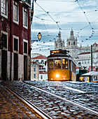 Romantische Atmosphäre in den alten Straßen von Alfama mit der Burg im Hintergrund und Straßenbahnnummer 28, Lissabon, Portugal, Europa
