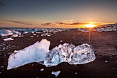 Gebrochenes Eis von angespülten Eisbergen am schwarzen Strand von Jokulsarlon bei Sonnenuntergang, Jokulsarlon, Südostisland, Island, Polarregionen