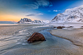 Das erste Licht der Morgendämmerung beleuchtet die vom Wind und dem kalten Meer geformten Felsen von Uttakleiv, Lofoten, Arktis, Norwegen, Skandinavien, Europa