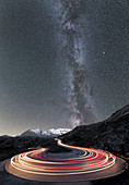 Milky Way and lights of car traces, Bernina Pass, Poschiavo Valley, Engadine, Canton of Graubunden, Switzerland, Europe