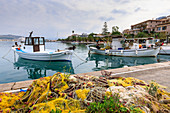 Colourful fishing nets on quay, boats, man mending nets, waterfront, Nafplio (Nafplion), Argolic Gulf, Peloponnese, Greece, Europe