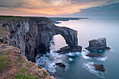 Colourful dawn sky above the Green Bridge of Wales natural arch in Pembrokeshire, Wales, United Kingdom, Europe