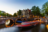 Keizergracht Canal at dusk, trailing light blur from a tourist boat, Amsterdam, North Holland, The Netherlands, Europe