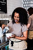Woman barista preparing a cup of coffee in a coffee shop.