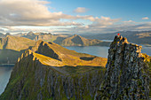 Man standing at the top of a pinnacle with a view over the landscape, Senja Island, Troms