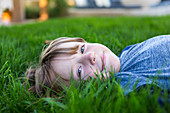 portrait of smiling 6 year old boy lying down in green grass