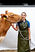 Landwirtin in grüner Schürze mit einer Guernsey-Kuh