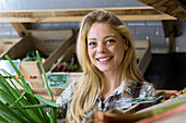 Smiling young woman holding spring onion in wicker basket